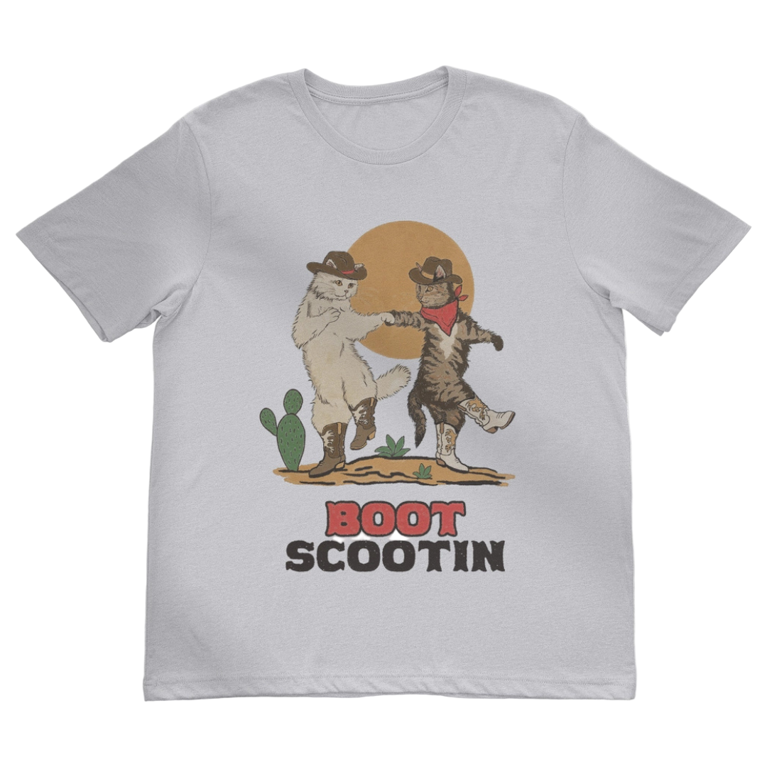 Two cats in cowboy hats and boots dancing in the desert. Natural tan shirt says, "Boot Scootin" country western font. 