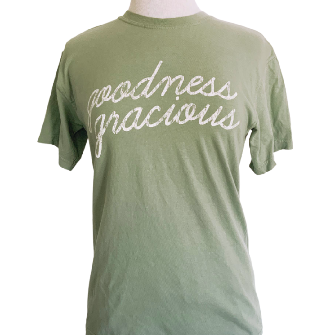 Sage green shirt says, "Goodness Gracious" screen-printed in white script. 