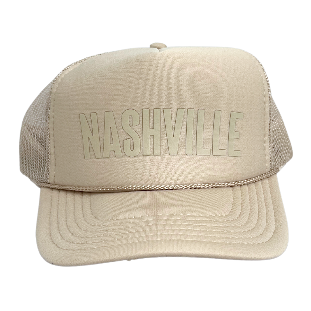 Beige trucker hat with foamy front and mesh sides; says, "Nashville" in beige block lettering. 