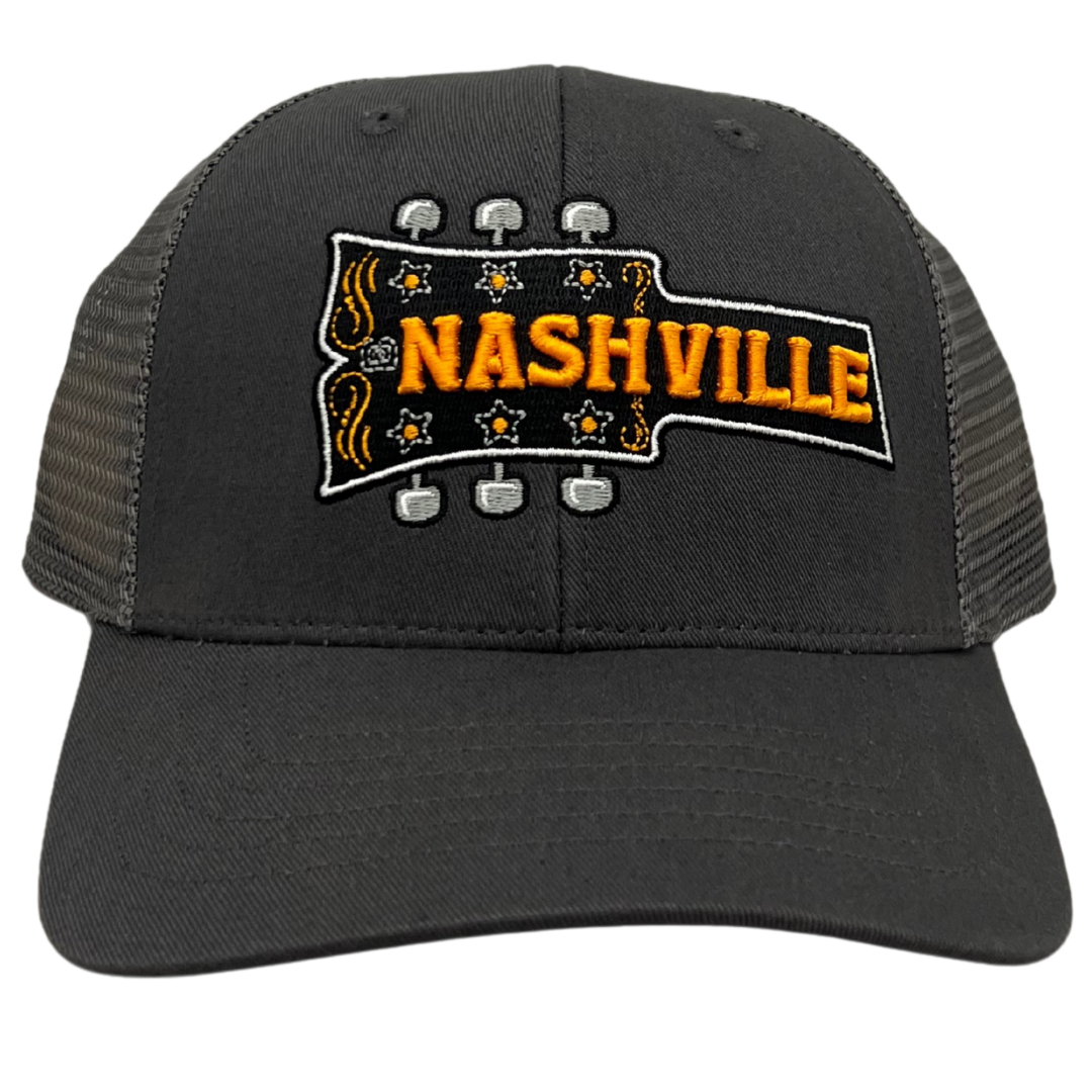 Gray trucker hat with embroidered Nashville guitar headstock design in orange and black with mesh back.