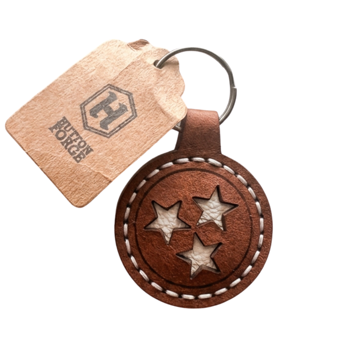 approx 2 in round leather keychain fob with white leather tristars. 