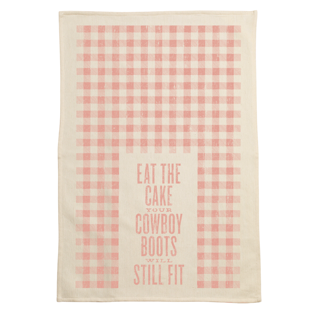 screen printed on cotton kitchen towel in pink, "eat the cake your cowboy boots will still fit"