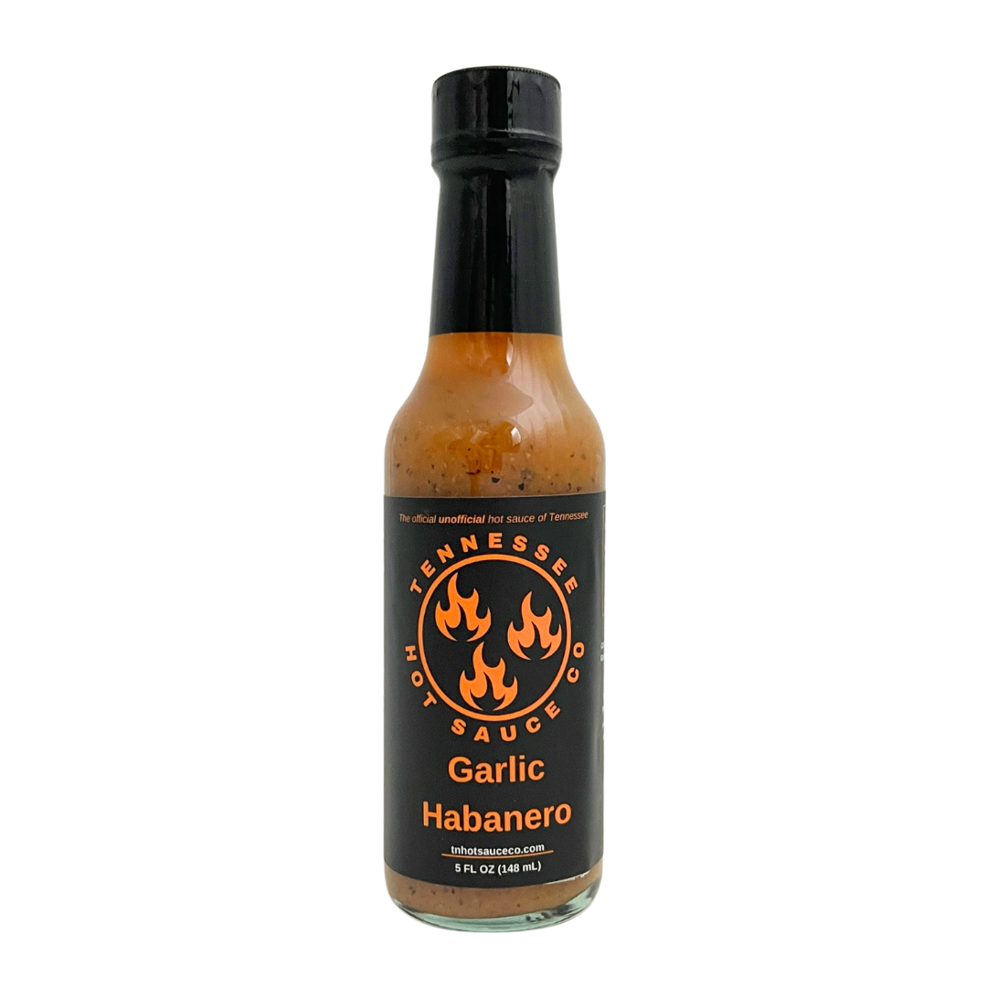Garlic Habanero sauce in a glass bottle. Comes with company logo taped on and a black cap.