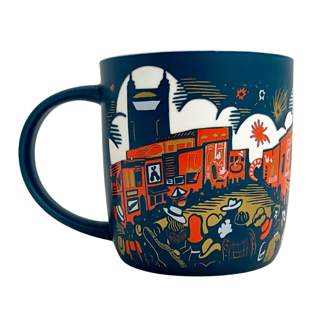 Mug featuring etched design of downtown Nashville. Blue mug with orange white and gold details.  