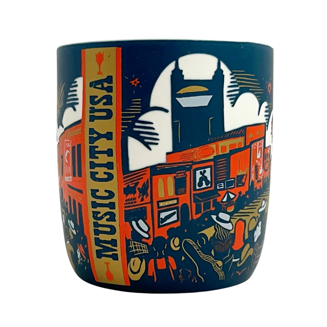 Mug featuring etched design of downtown Nashville. Blue mug with orange white and gold details.  