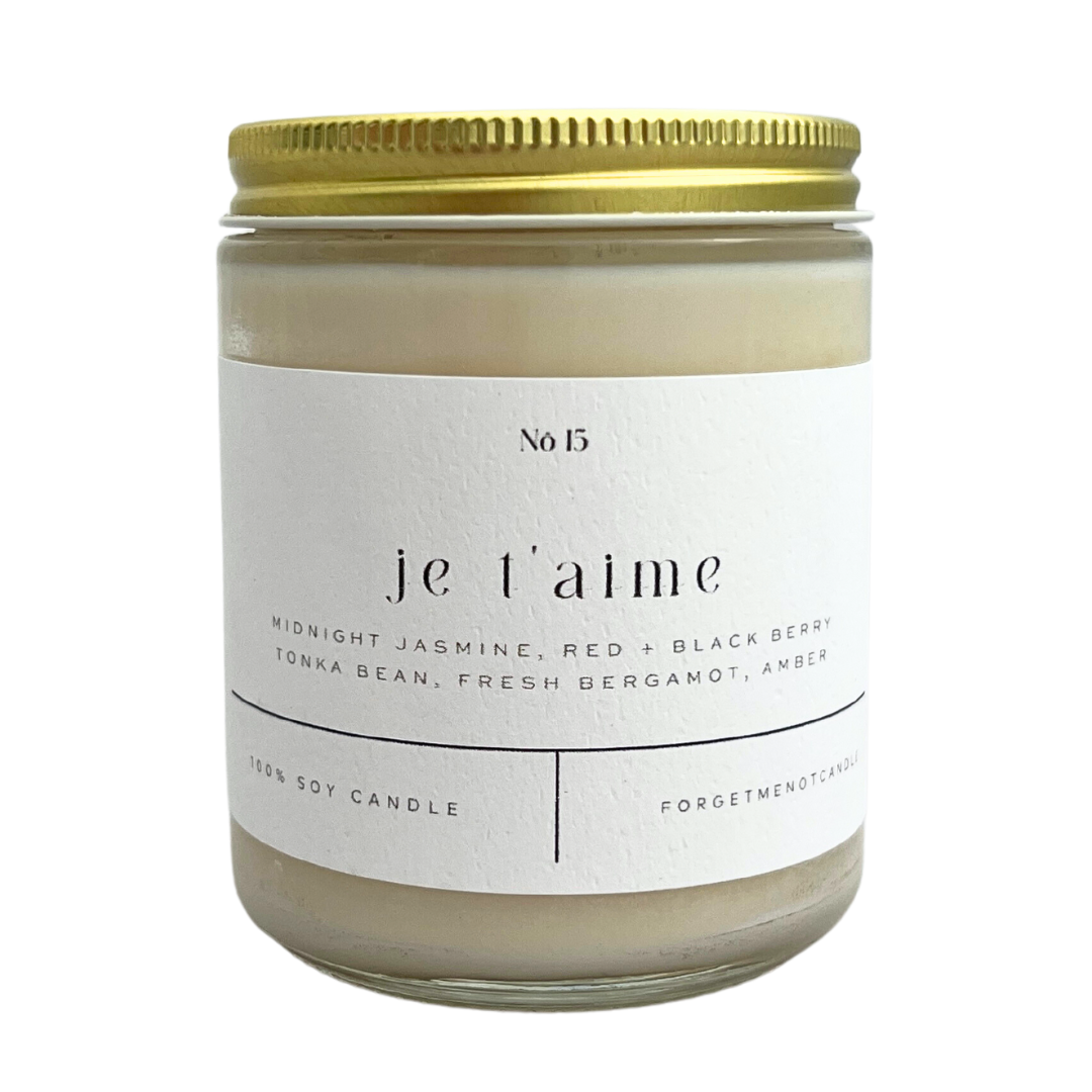 "Je T'aime" candle with scents of midnight jasmine, red + blackberry, tonka bean, fresh bergamot, and amber. In opaque white jar with gold lid. 