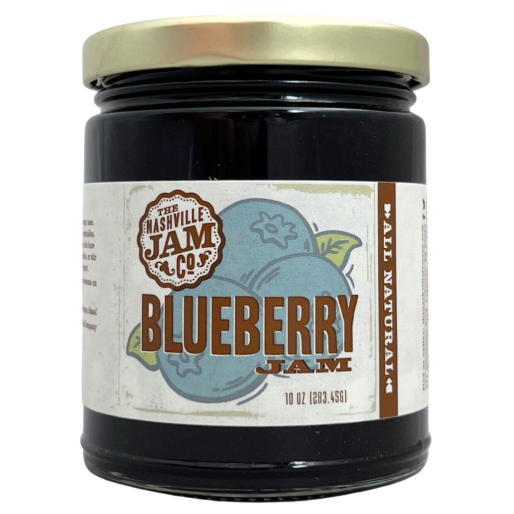 Blueberry jam in 10 oz clear glass jar with gold lid, label has illustration of blueberries. 