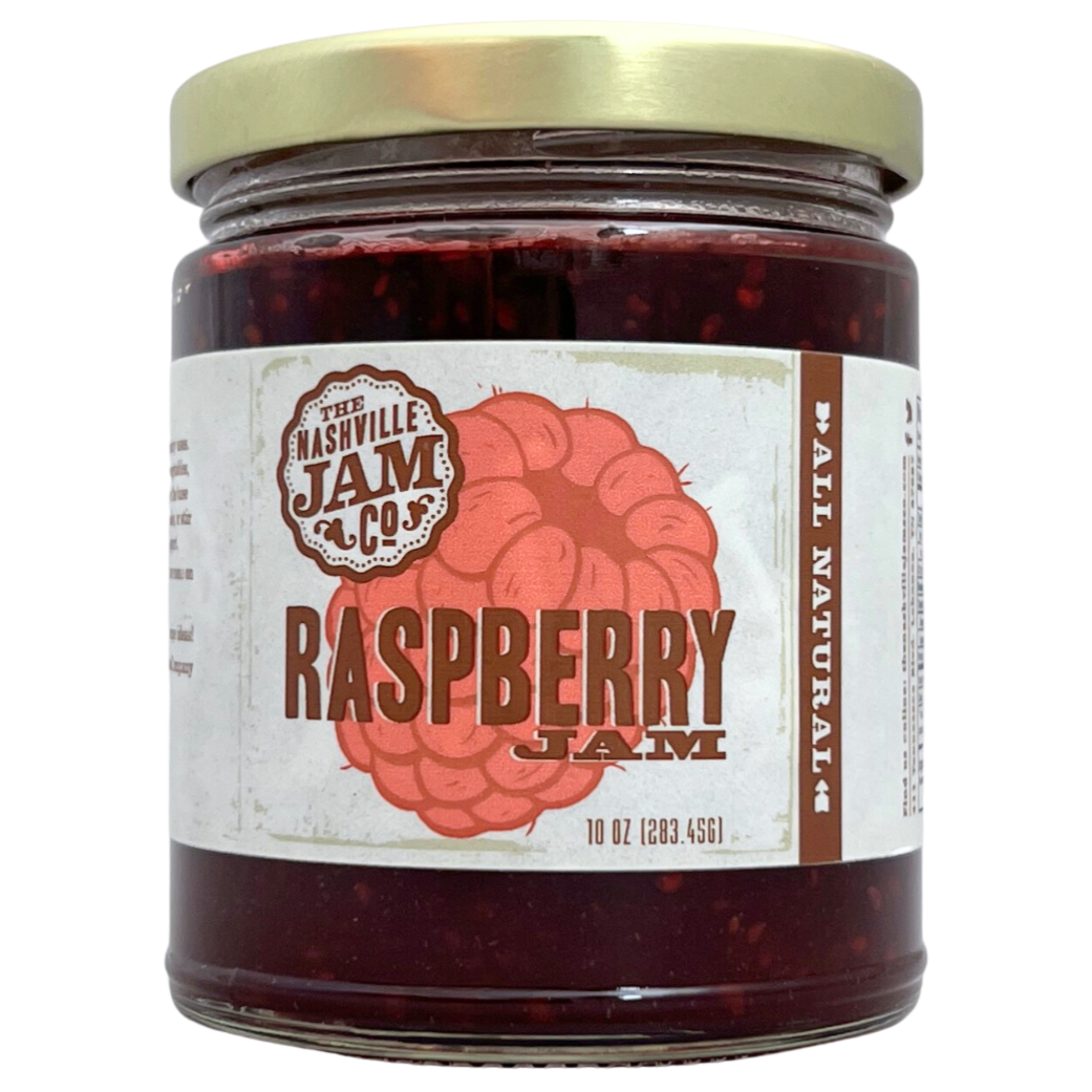 Raspberry jam in 10 oz clear glass jar with gold lid, label has illustration of a raspberry. 