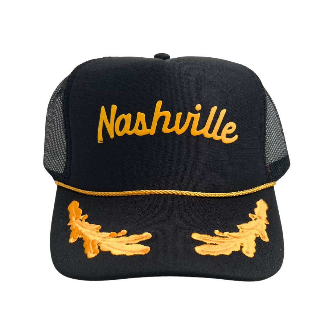 Black trucker hat with foamy front and mesh sides has "Nashville" and branches embroidered in gold.